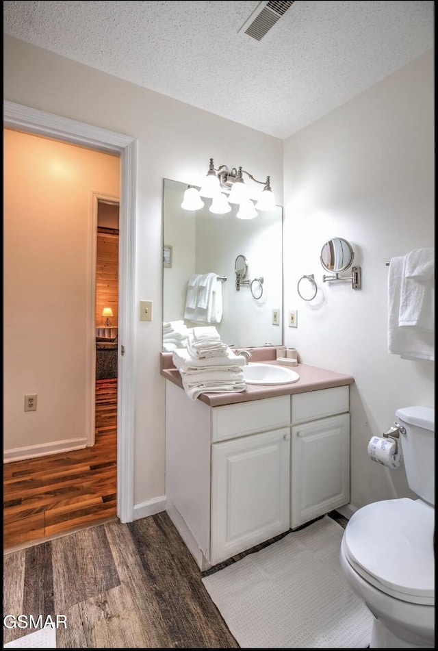 bathroom featuring hardwood / wood-style floors, vanity, toilet, and a textured ceiling