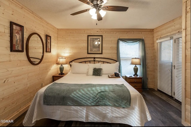 bedroom with dark hardwood / wood-style flooring, ceiling fan, wooden walls, and a textured ceiling