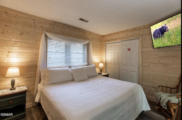 bedroom with dark hardwood / wood-style flooring, wooden walls, and a closet