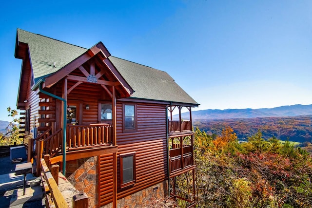 view of side of home with a mountain view and roof with shingles