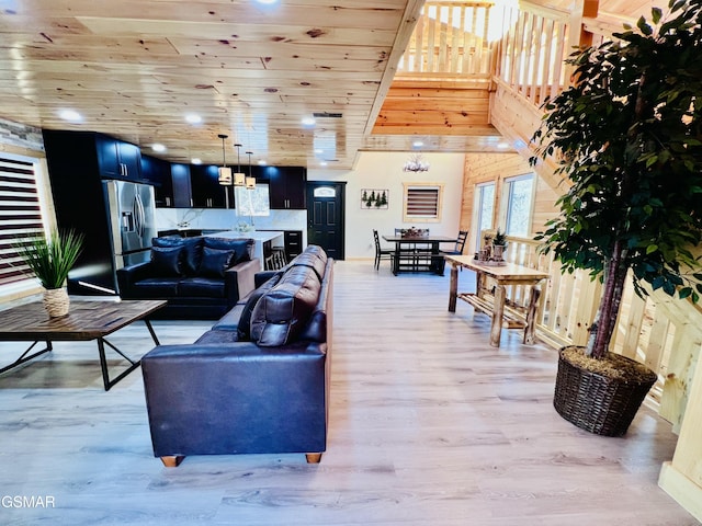 living room with light hardwood / wood-style floors, wooden ceiling, and a towering ceiling