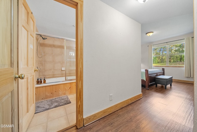 interior space featuring baseboards,  shower combination, and wood finished floors