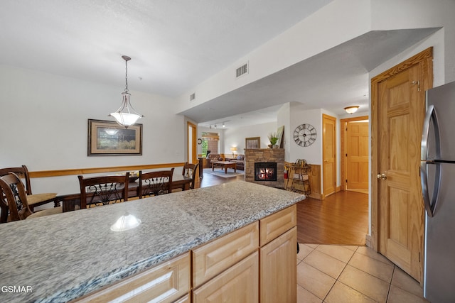 kitchen with visible vents, freestanding refrigerator, pendant lighting, open floor plan, and light tile patterned floors