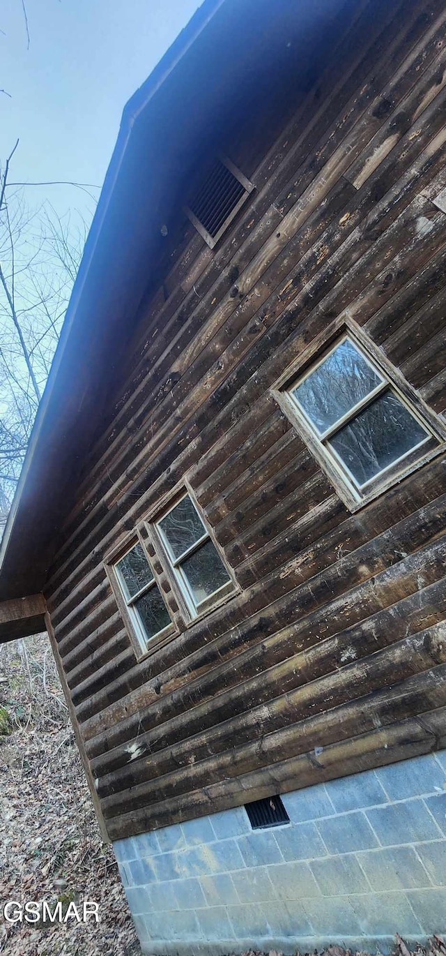 view of side of home with crawl space and log siding