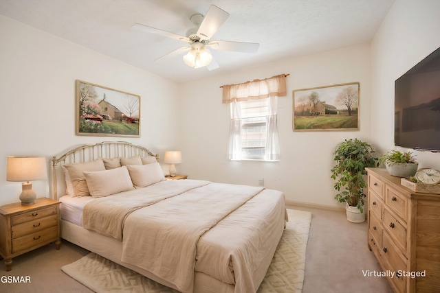 bedroom featuring a ceiling fan, light colored carpet, and baseboards