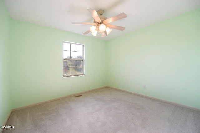 carpeted spare room with visible vents, baseboards, and ceiling fan