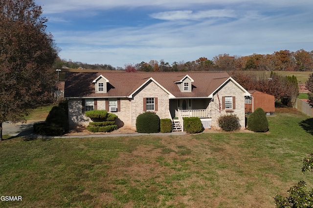 view of front of house with a porch, fence, a front yard, a shingled roof, and brick siding