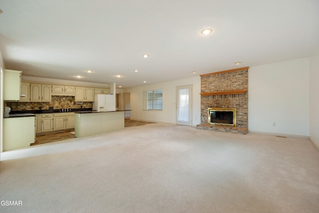 unfurnished living room featuring baseboards, recessed lighting, a sink, a brick fireplace, and light colored carpet