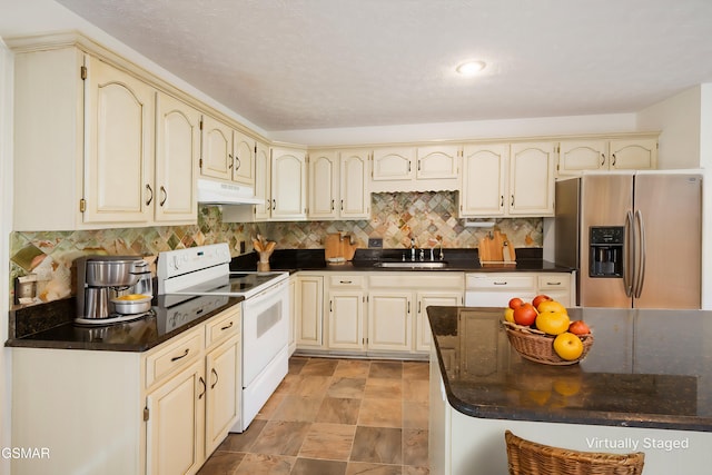 kitchen with white electric range oven, cream cabinetry, stainless steel fridge, and under cabinet range hood