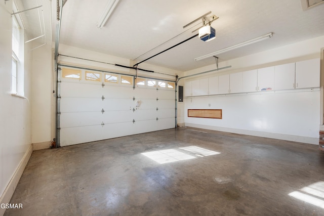 garage with electric panel, a garage door opener, and baseboards