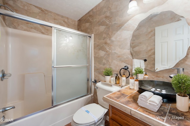 full bathroom with combined bath / shower with glass door, toilet, tile walls, and vanity