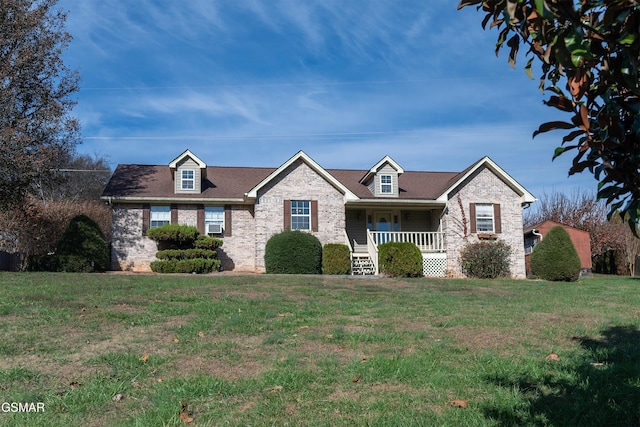 view of front of house featuring a front yard, brick siding, and covered porch