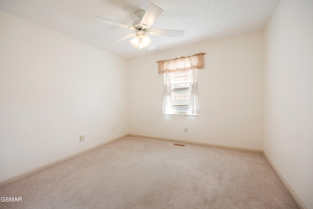 carpeted empty room with baseboards, visible vents, a textured ceiling, and ceiling fan