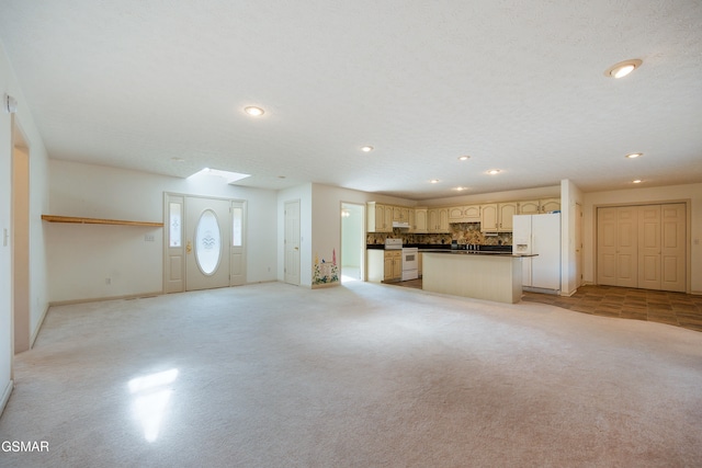 unfurnished living room featuring a skylight, recessed lighting, baseboards, and light carpet