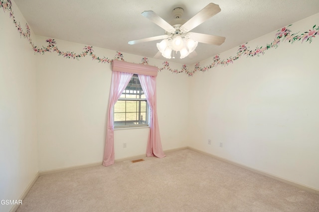 carpeted spare room featuring a ceiling fan, baseboards, and visible vents