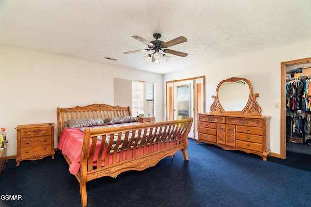 carpeted bedroom with visible vents, a textured ceiling, a closet, ceiling fan, and a spacious closet