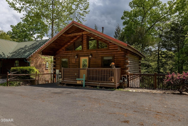 log-style house featuring fence, log exterior, driveway, and metal roof