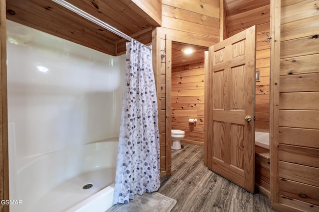 bathroom with wooden walls, toilet, a shower stall, and wood finished floors