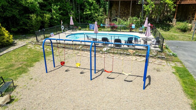 view of community with fence, a swimming pool, and playground community