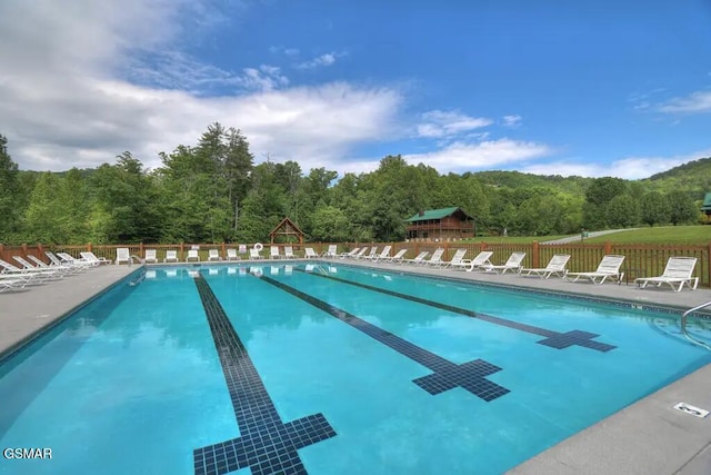 community pool with fence and a forest view