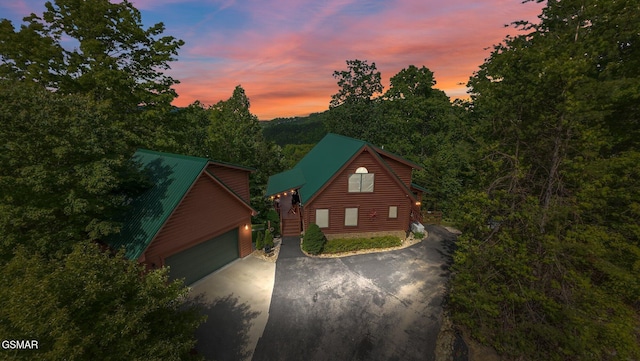 view of front of property featuring a detached garage, stairway, asphalt driveway, and an outbuilding