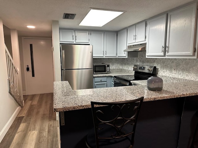 kitchen with kitchen peninsula, stainless steel appliances, and light stone countertops