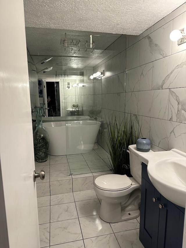 bathroom featuring a textured ceiling, vanity, a bath, and tile walls