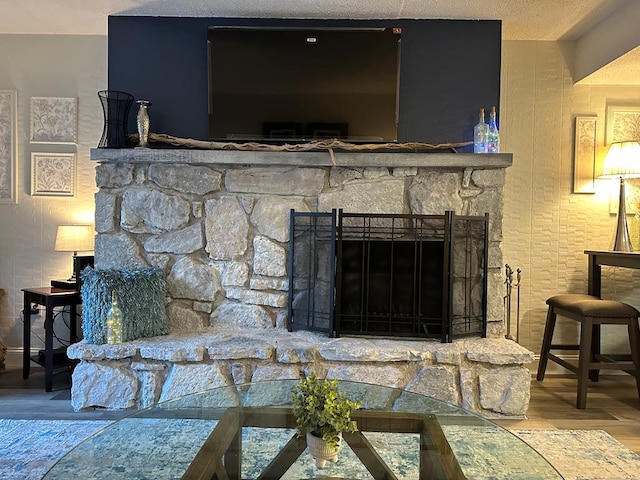 interior details with hardwood / wood-style floors, a textured ceiling, and a stone fireplace