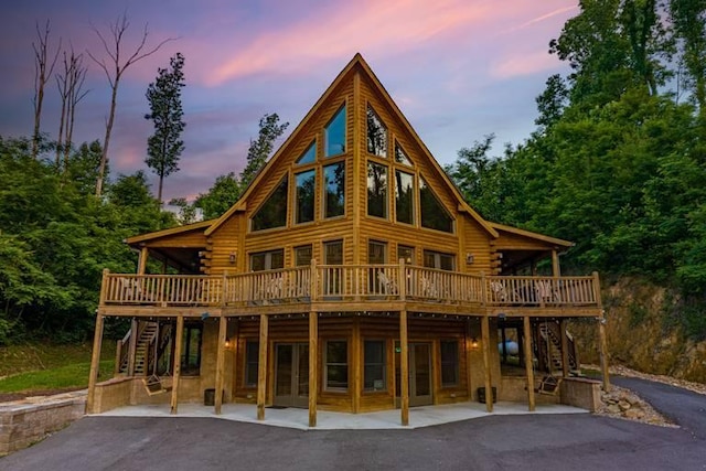 back house at dusk featuring a patio area and a wooden deck