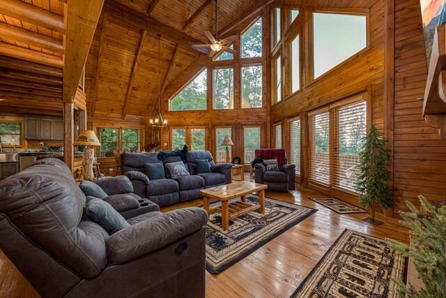 living room featuring beam ceiling, high vaulted ceiling, wood ceiling, ceiling fan with notable chandelier, and light wood-type flooring