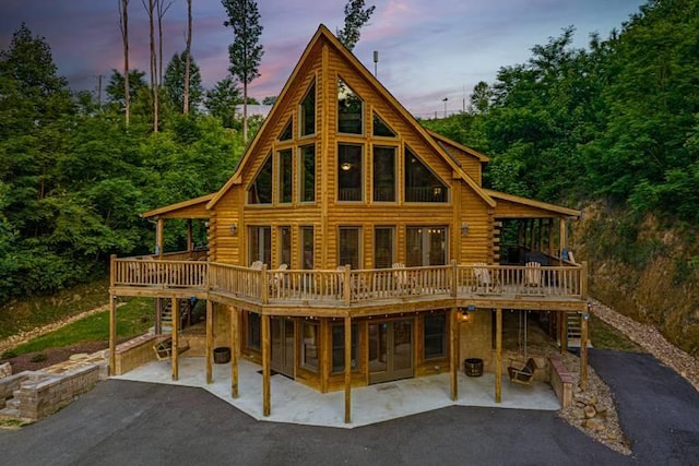 back house at dusk featuring a patio and a wooden deck