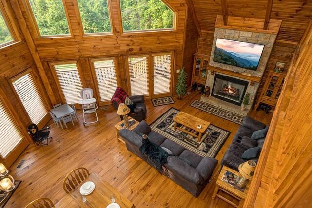 living room with a high ceiling, a stone fireplace, and plenty of natural light