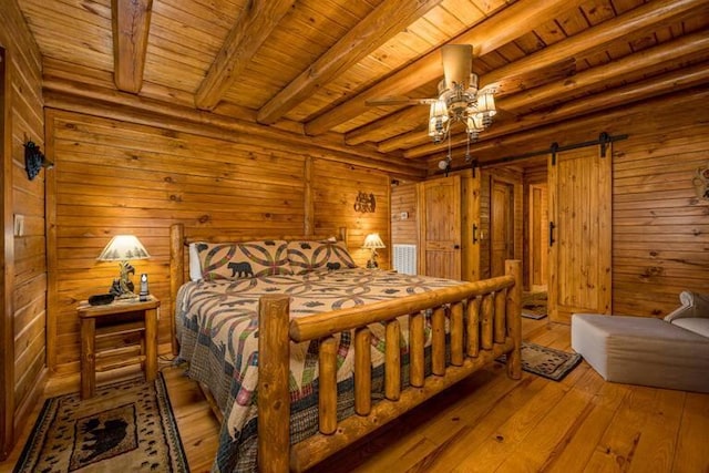 bedroom with wood ceiling, ceiling fan, a barn door, beamed ceiling, and light hardwood / wood-style floors