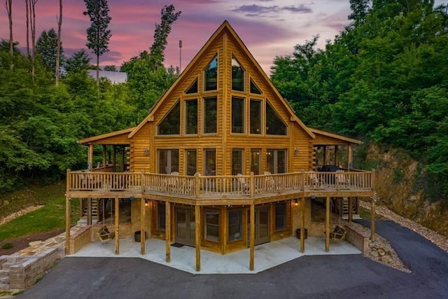 back house at dusk with a patio and a wooden deck