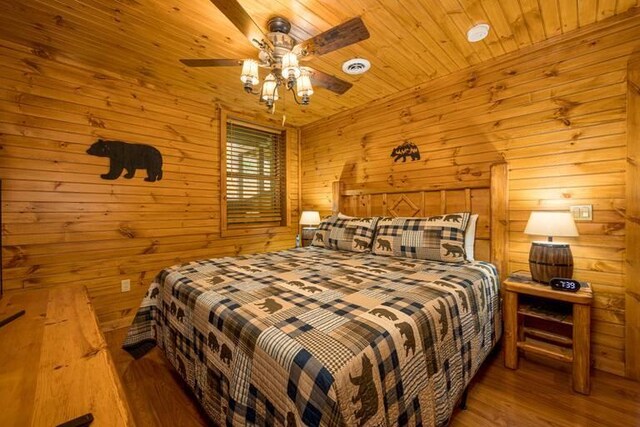 bedroom featuring hardwood / wood-style floors, ceiling fan, wood ceiling, and wooden walls