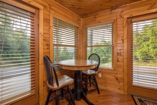 dining area featuring hardwood / wood-style floors, wooden ceiling, and wooden walls