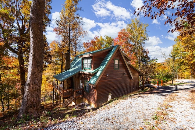 view of home's exterior featuring metal roof, a porch, and faux log siding