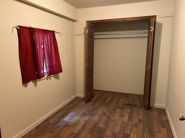 unfurnished bedroom featuring a closet and dark hardwood / wood-style flooring