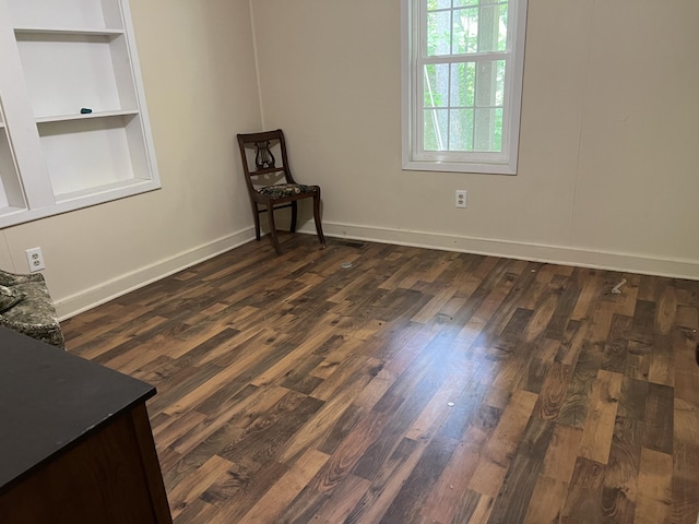 unfurnished room with built in shelves and dark hardwood / wood-style floors