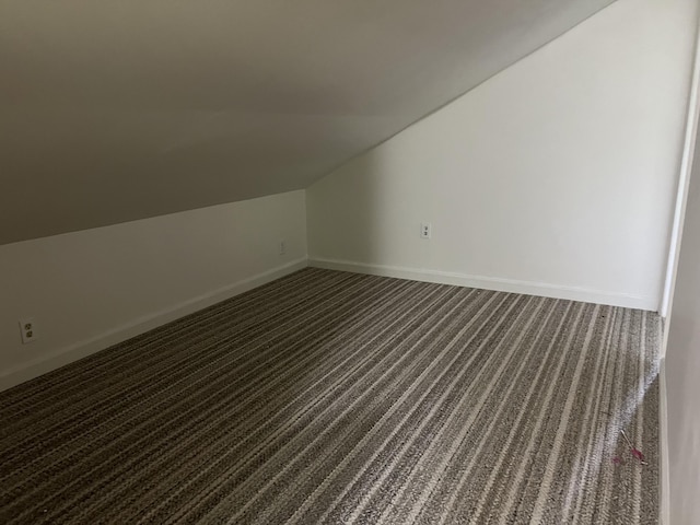 additional living space featuring dark carpet and lofted ceiling