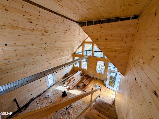 unfurnished living room with light wood-type flooring, wooden ceiling, and wooden walls