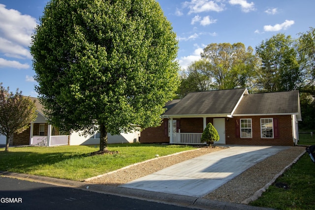 view of front of property featuring a porch, driveway, a front lawn, and brick siding