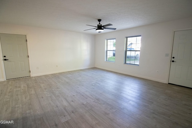 unfurnished living room featuring a textured ceiling, wood finished floors, baseboards, and a ceiling fan