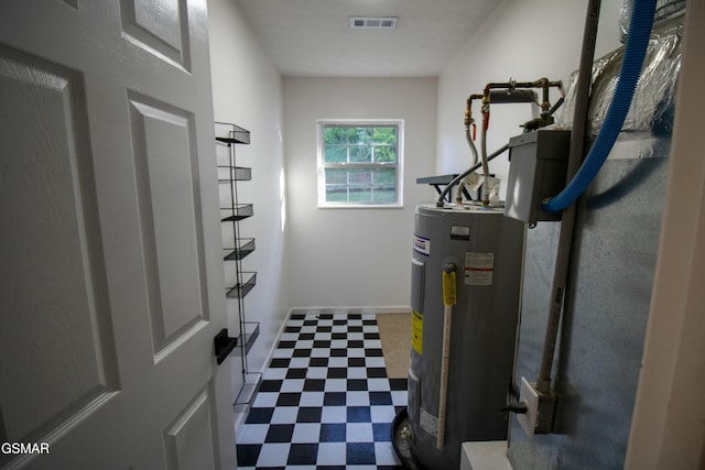 utility room featuring electric water heater and visible vents