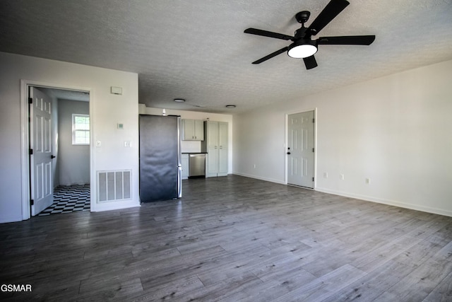 unfurnished living room featuring dark wood-style floors, a textured ceiling, a ceiling fan, and visible vents