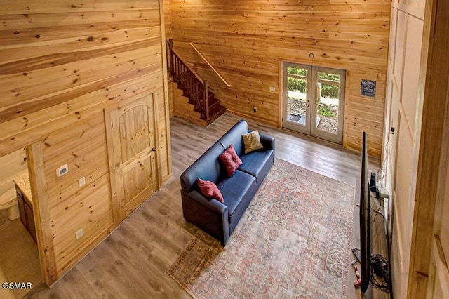 interior space with french doors, stairway, wood walls, and wood finished floors