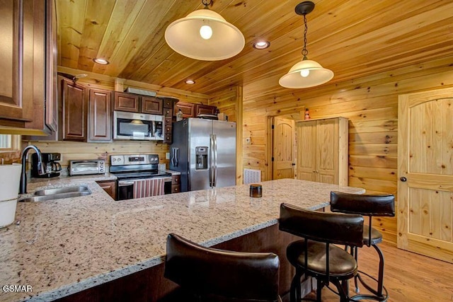 kitchen with light stone countertops, wood ceiling, appliances with stainless steel finishes, and a sink