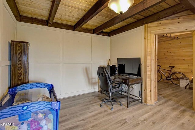 office space with wooden ceiling, light wood-style flooring, a decorative wall, and beamed ceiling