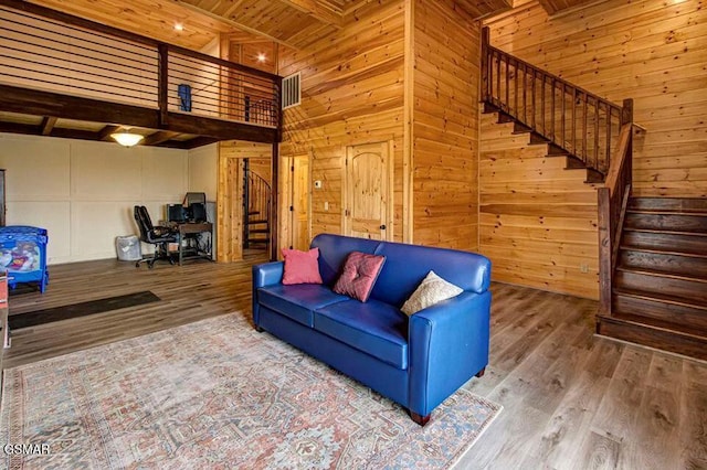 living room with wood ceiling, wood finished floors, wooden walls, and stairs