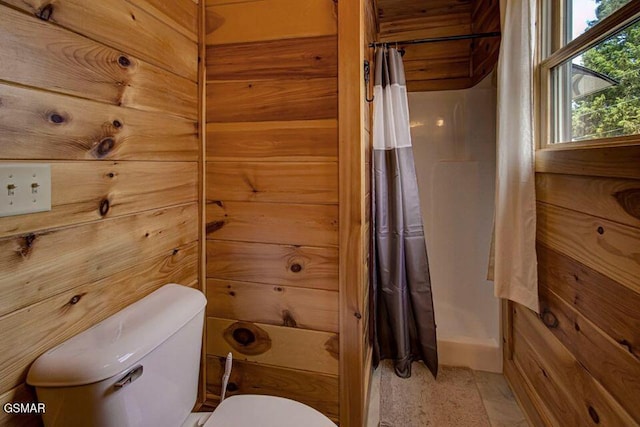 bathroom featuring curtained shower, wood walls, and toilet